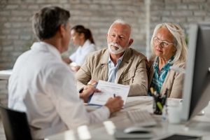 A professional patient advocate meeting with an older couple to discuss medical records and financial assistance options for mesothelioma.