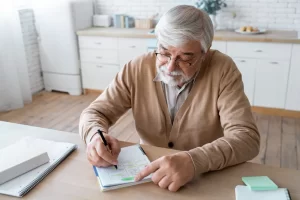 a senior man writing a work history timeline as part of asbestos exposure mapping