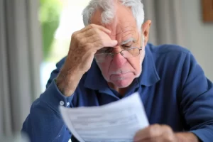 A senior veteran looking concerned while reviewing medical records for veterans' benefits eligibility